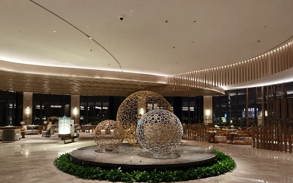 Custom openwork stainless steel sphere sculpture installation in a luxury hotel lobby