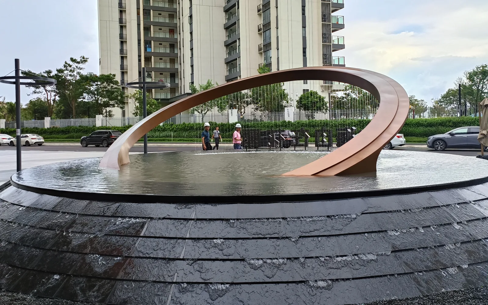 Large stainless steel water curtain public art sculpture installed in an urban plaza